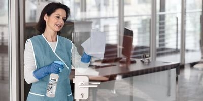 Person cleaning a glass door in an office building Person cleaning a glass door in an office building
