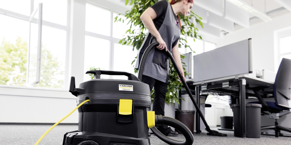 A woman cleaning an office with a vacuum cleaner
