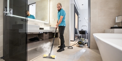Person cleaning a hotel bathroom with a steam cleaner Person cleaning a hotel bathroom with a steam cleaner