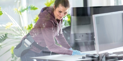 Person cleaning a desk with a disinfectant cloth