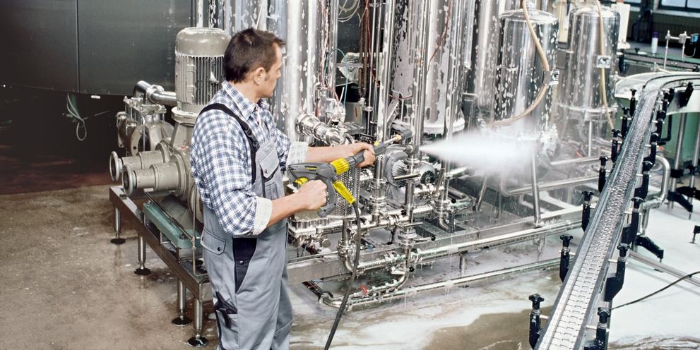 A man cleans conveyor belts with a high-pressure cleaner