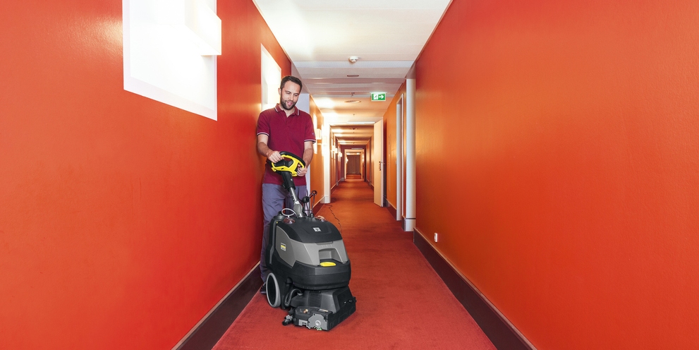 Floor cleaning with a scrubber dryer A person cleaning the carpet with a Kärcher scrubber dryer