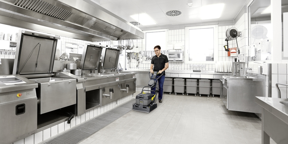 The scrubber dryer in action A person cleaning the kitchen floor with a Kärcher scrubber dryer