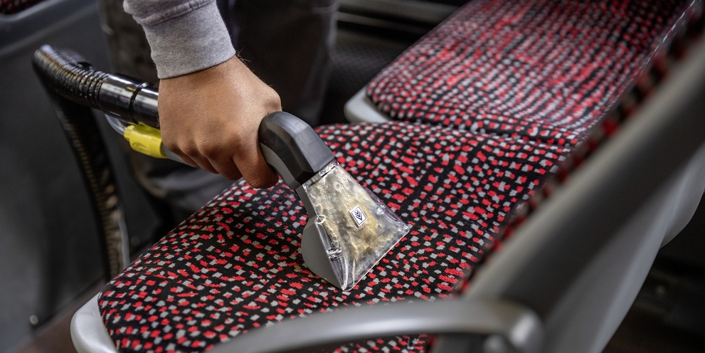 A person cleaning the upholstery of a seat with a mini scrubber dryer