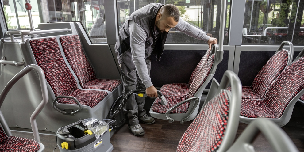 A person cleaning the interior of a bus with a mini scrubber dryer