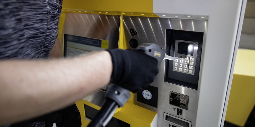 A person cleans a ticket machine with a dry ice blaster