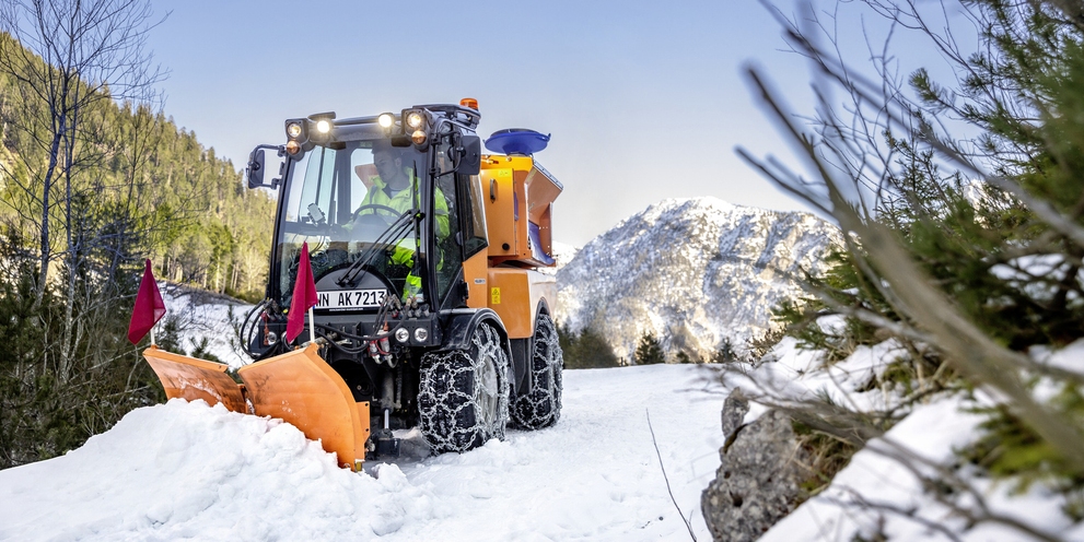 A snowplough pushing large masses of snow from a mountain road