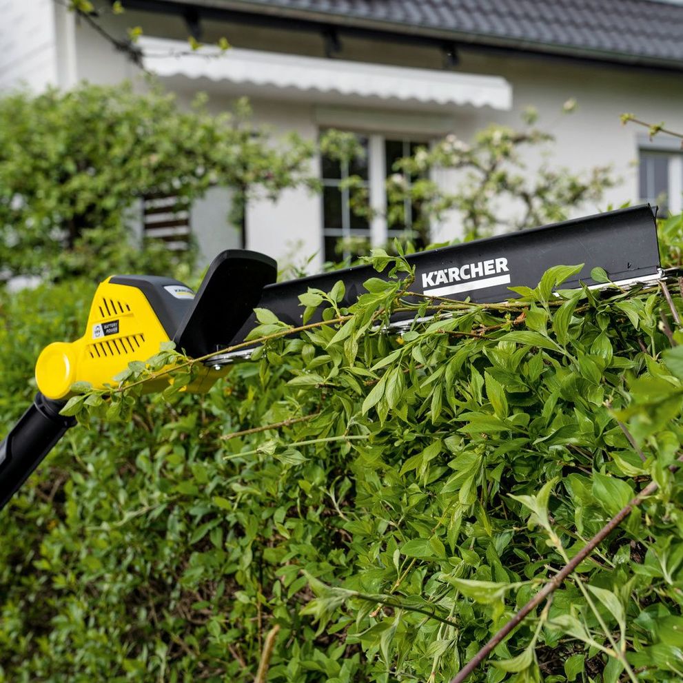 The Kärcher battery hedge trimmer with hedge broom in use on a hedge