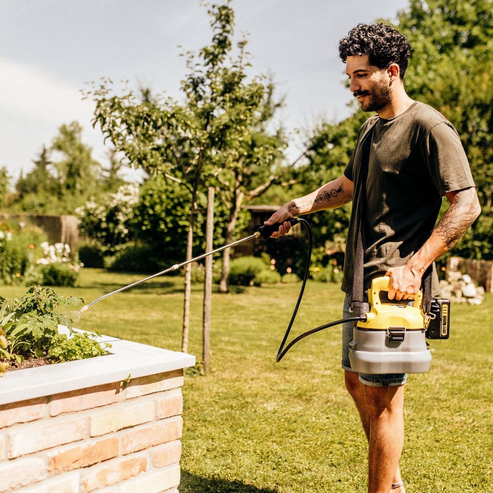 Person waters plants with the Kärcher cordless pressure sprayer