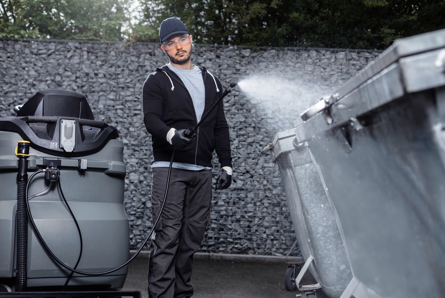 Person cleaning rubbish bins with Kärcher spray disinfection attachment kit for scrubber dryers