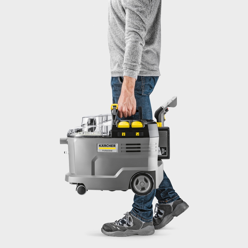A man carries a Kärcher Puzzi 9/1 Bp