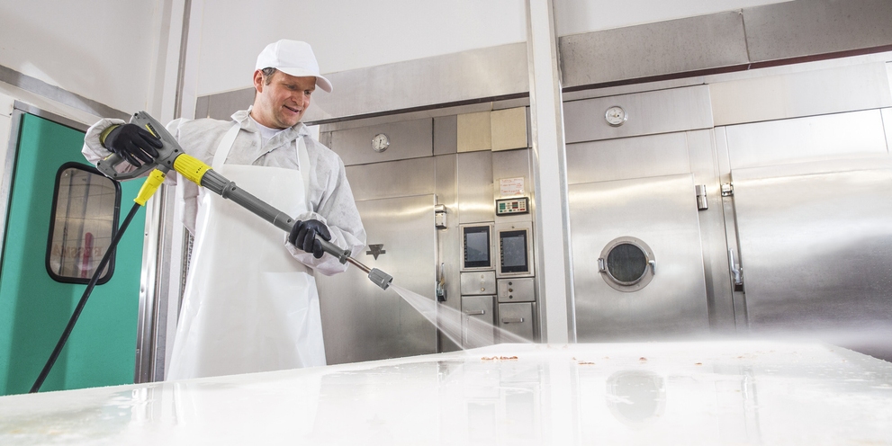 Butcher disinfects worktop with a Kärcher high-pressure cleaner