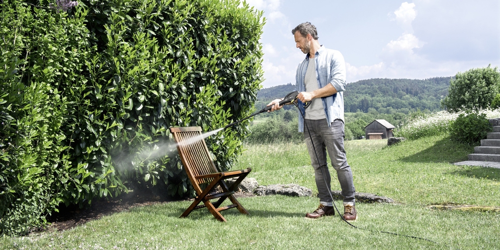 Man is cleaning garden furniture with a Kärcher pressure washer