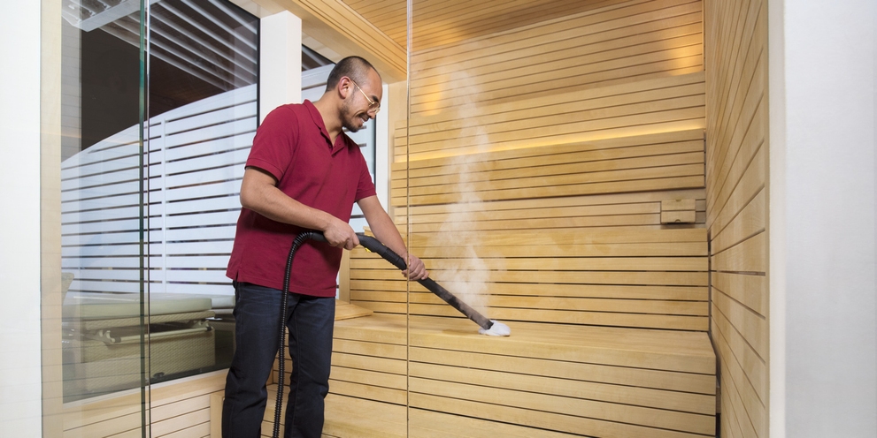 Person disinfecting sauna with a Kärcher steam cleaner