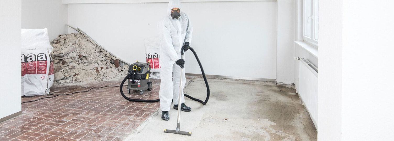 A person in white protective clothing cleans the floor of a refurbished flat from residues with a Kärcher vacuum cleaner