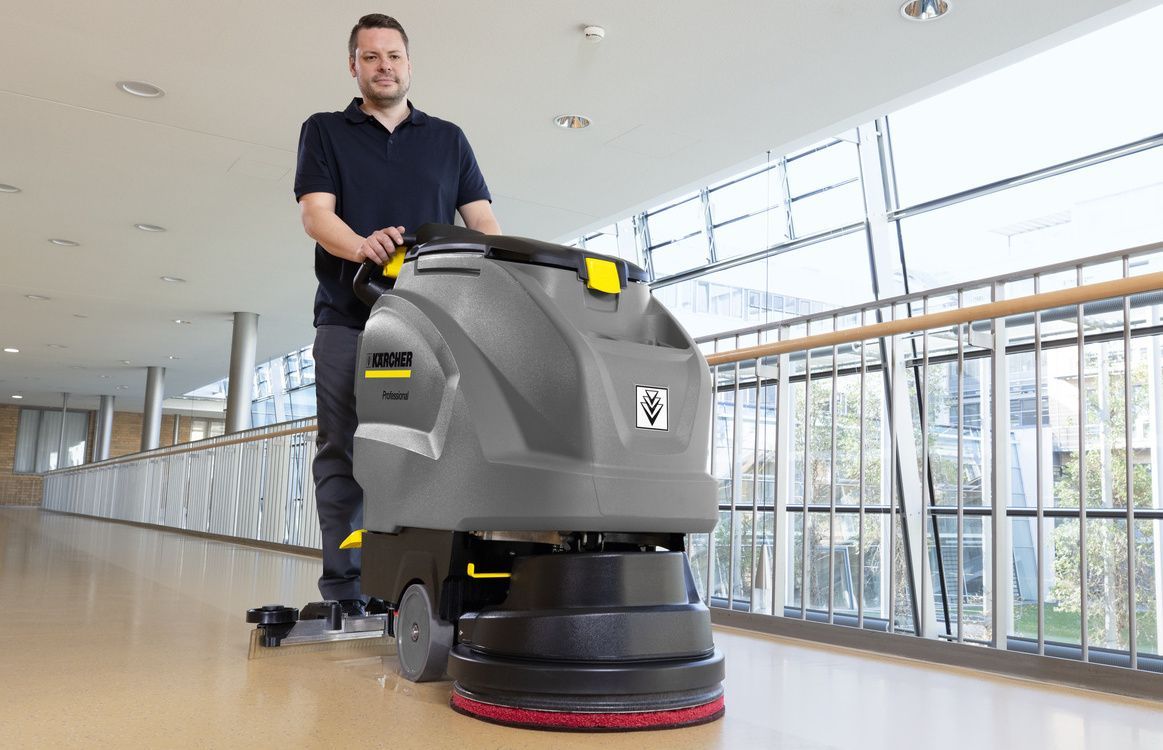 Man seen cleaning a laminate floor using a Kärcher walk-behind scrubber dryer