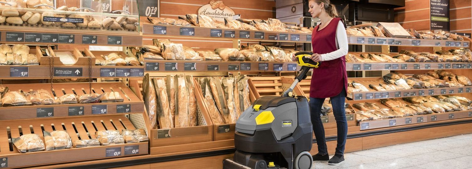 Taking care of the cleaning machines a person cleans the floor of a supermarket