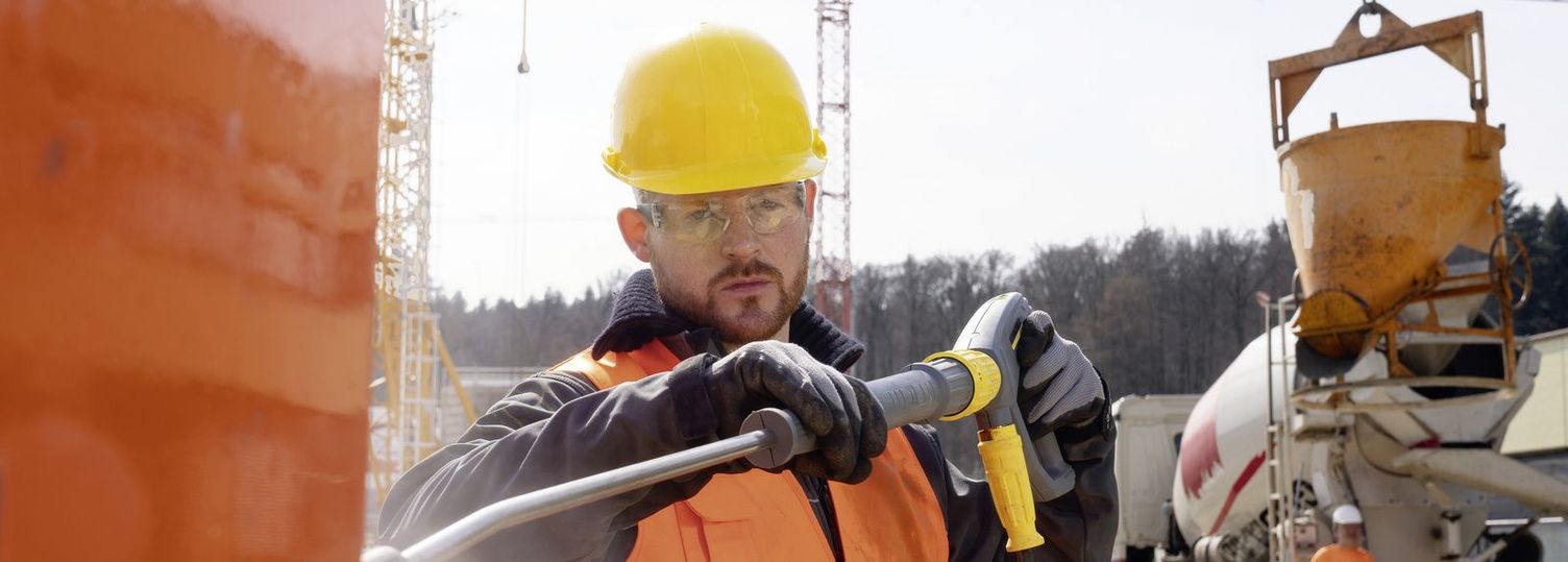 a person with a safety vest cleans a construction container with a Kärcher high-pressure cleaner