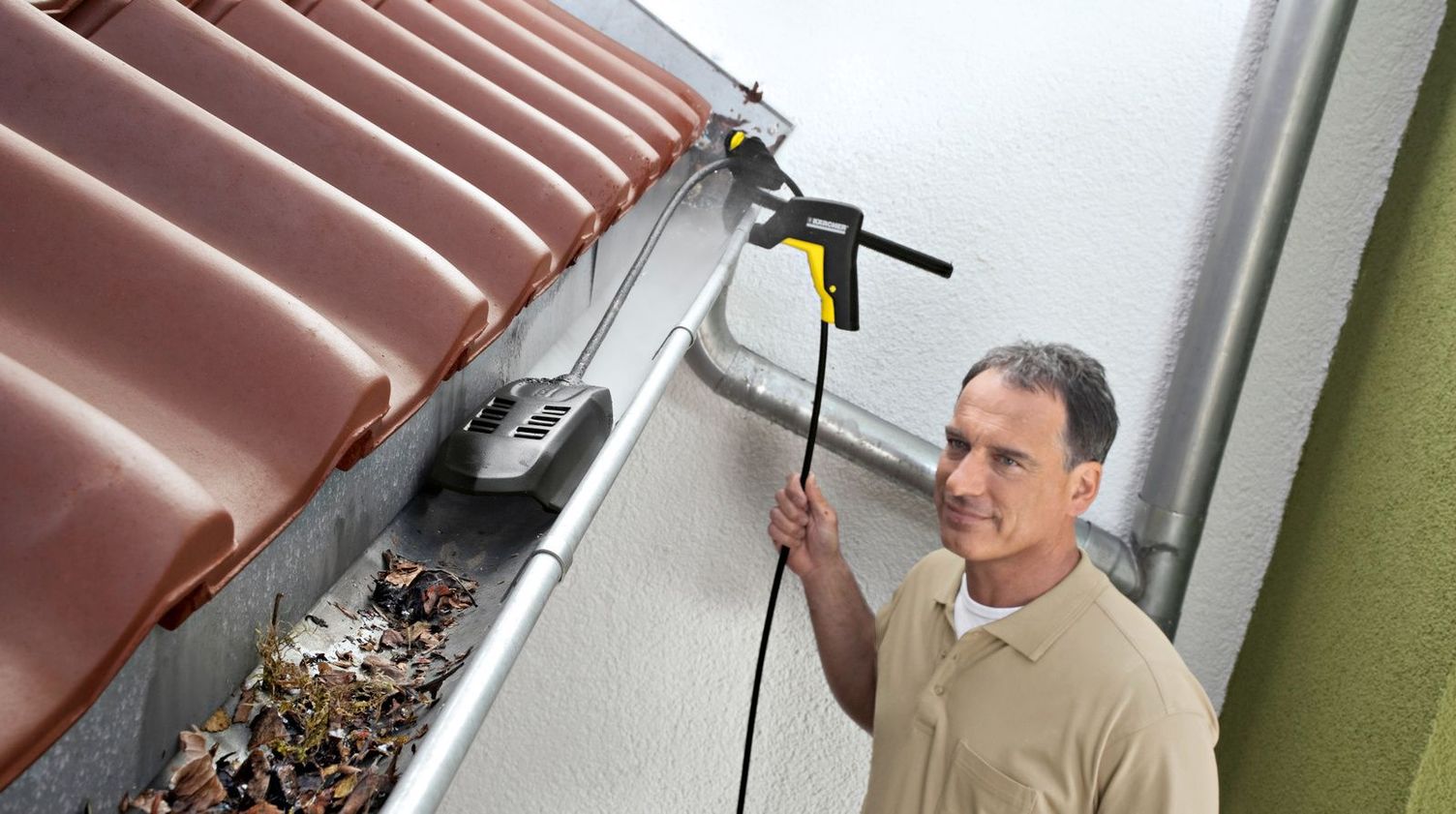 A man cleans gutters with a Kärcher gutter cleaning set