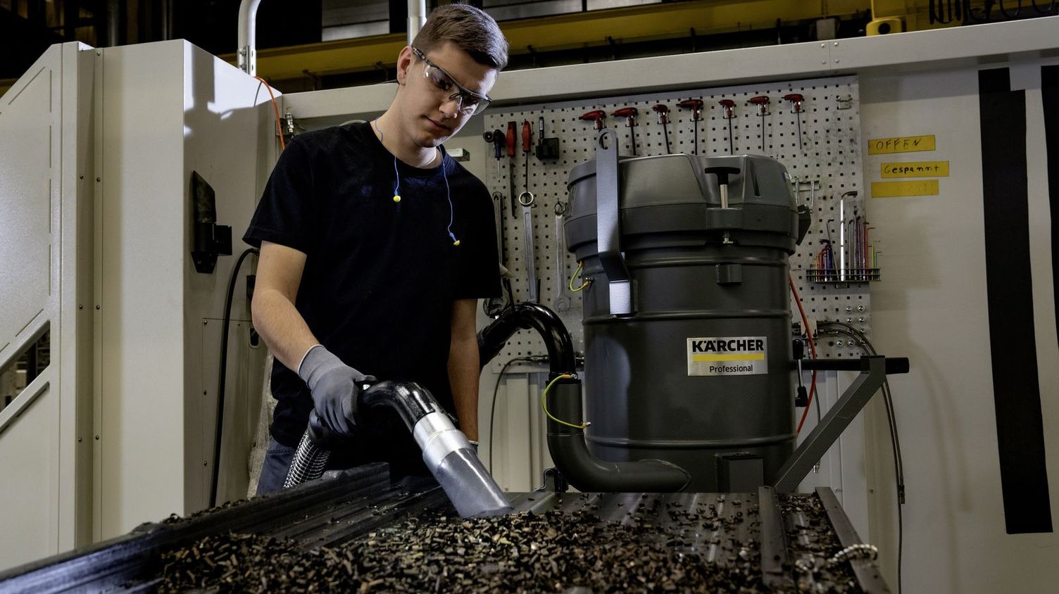 A person sucks swarf from a work surface with a Kärcher Industrial Deduster