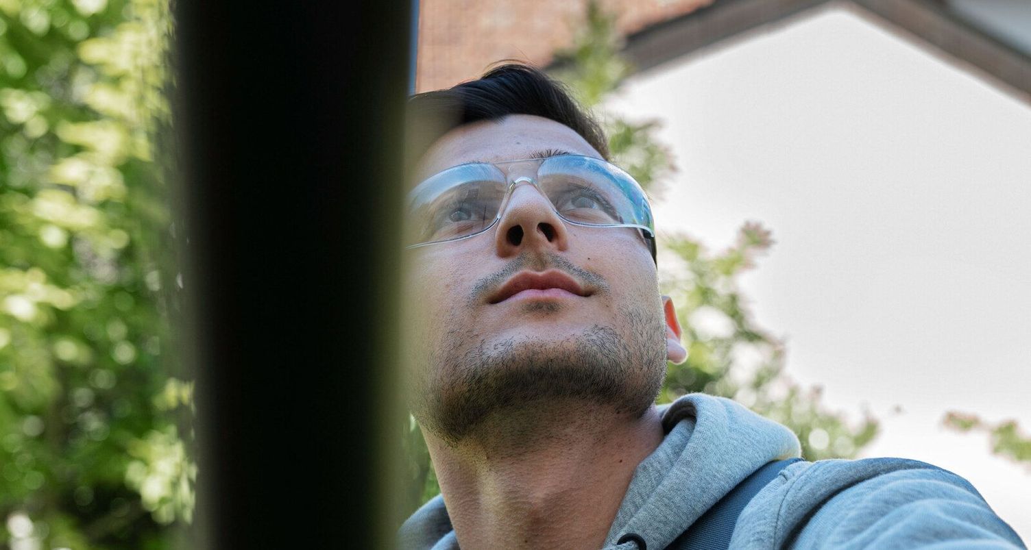 Glass facade cleaning A person wearing protective eyewear cleans a glass surface with a telescopic water-fed pole