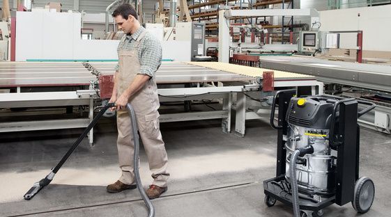 Industrial vacuum cleaner for wood dust extraction A person cleans the floor of a workshop using a Kärcher Safety Vacuum Cleaner