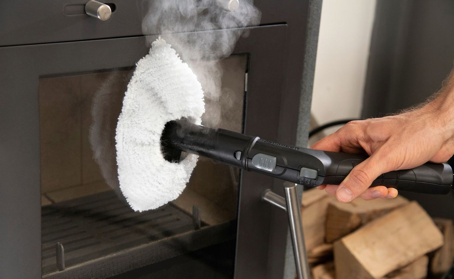 The glass pane on a stove is cleaned with a Kärcher steam cleaner