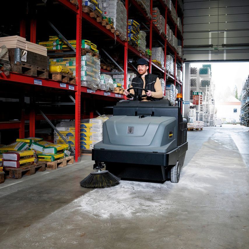 Ride-on vacuum sweeper in use Man seen cleaning a warehouse using a Kärcher ride-on vacuum sweeper
