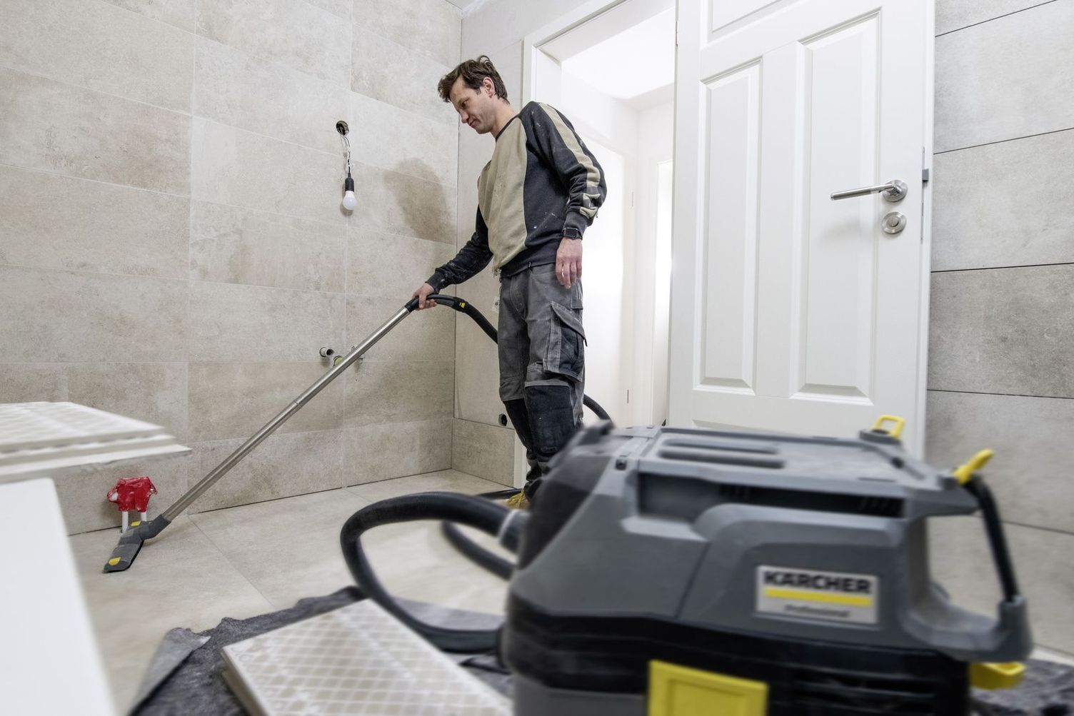 A person cleans the marble floor of a bathroom with a Kärcher device
