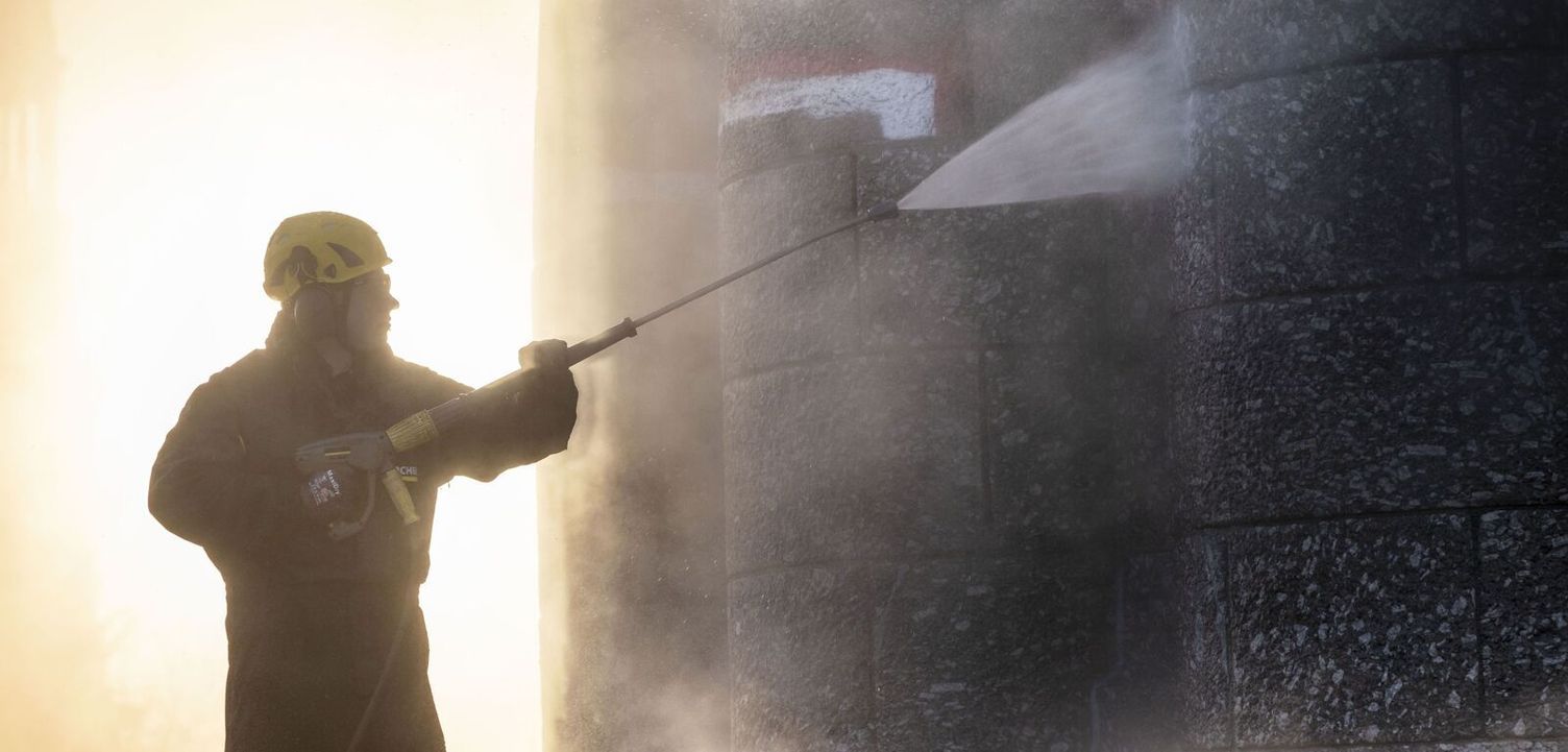 Pressure washing is an ideal method for deep cleaning natural stone surfaces A person wearing protective clothing and a helmet cleans a natural stone facade with a Kärcher Pressure Washer.