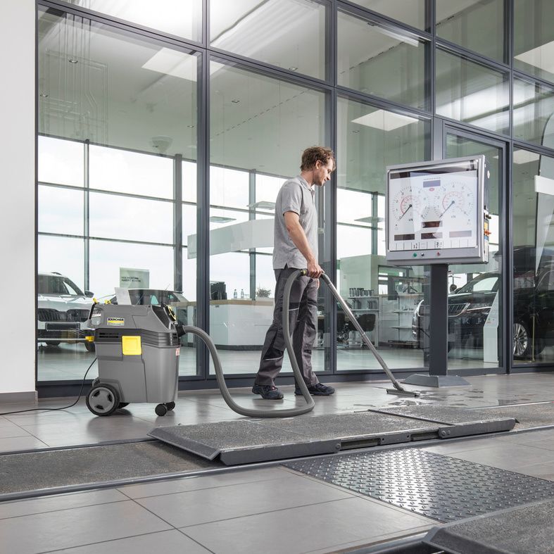 Person uses Kärcher wet vacuum cleaner on tiled floor in car dealership