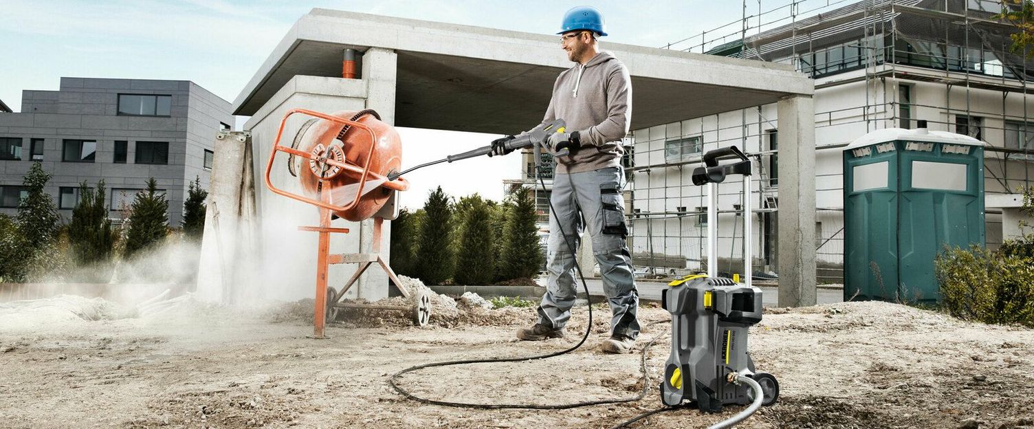 Portable cold-water units on the construction site for cleaning construction machinery A person cleans a piece of construction equipment with a Kärcher Cold Water High-Pressure Cleaner