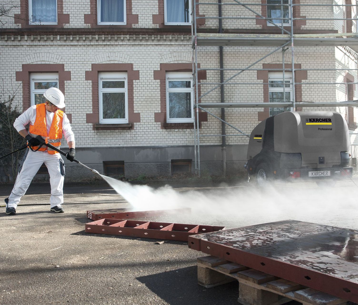 A person wearing protective clothing and a helmet is cleaning precast concrete mould with a Kärcher Ultra-High-Pressure Cleaner