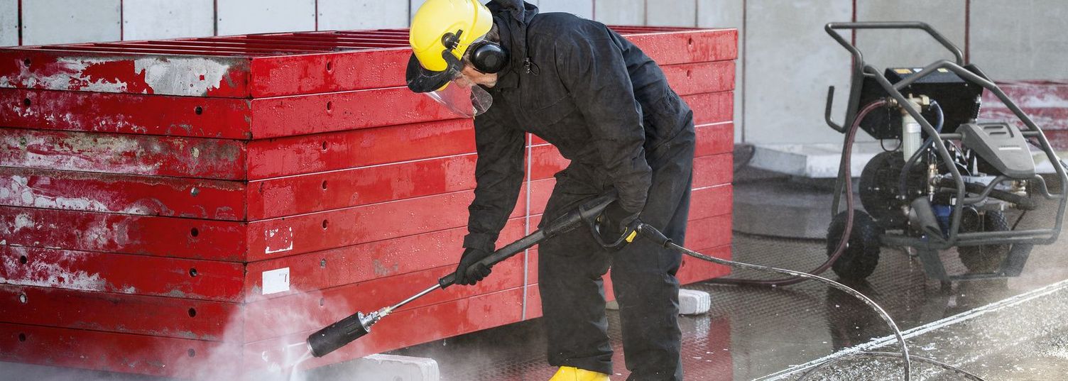 A person wearing protective clothing is cleaning formwork with a Kärcher Ultra-High-Pressure Cleaner