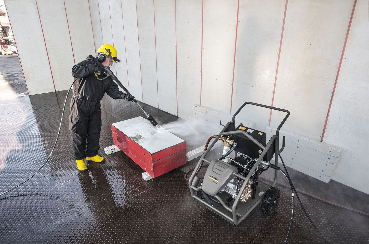 A person wearing protective clothing and a helmet is cleaning formwork with a Kärcher Ultra-High-Pressure Cleaner