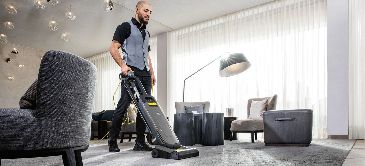A man is cleaning the carpet with a Kärcher carpet cleaner