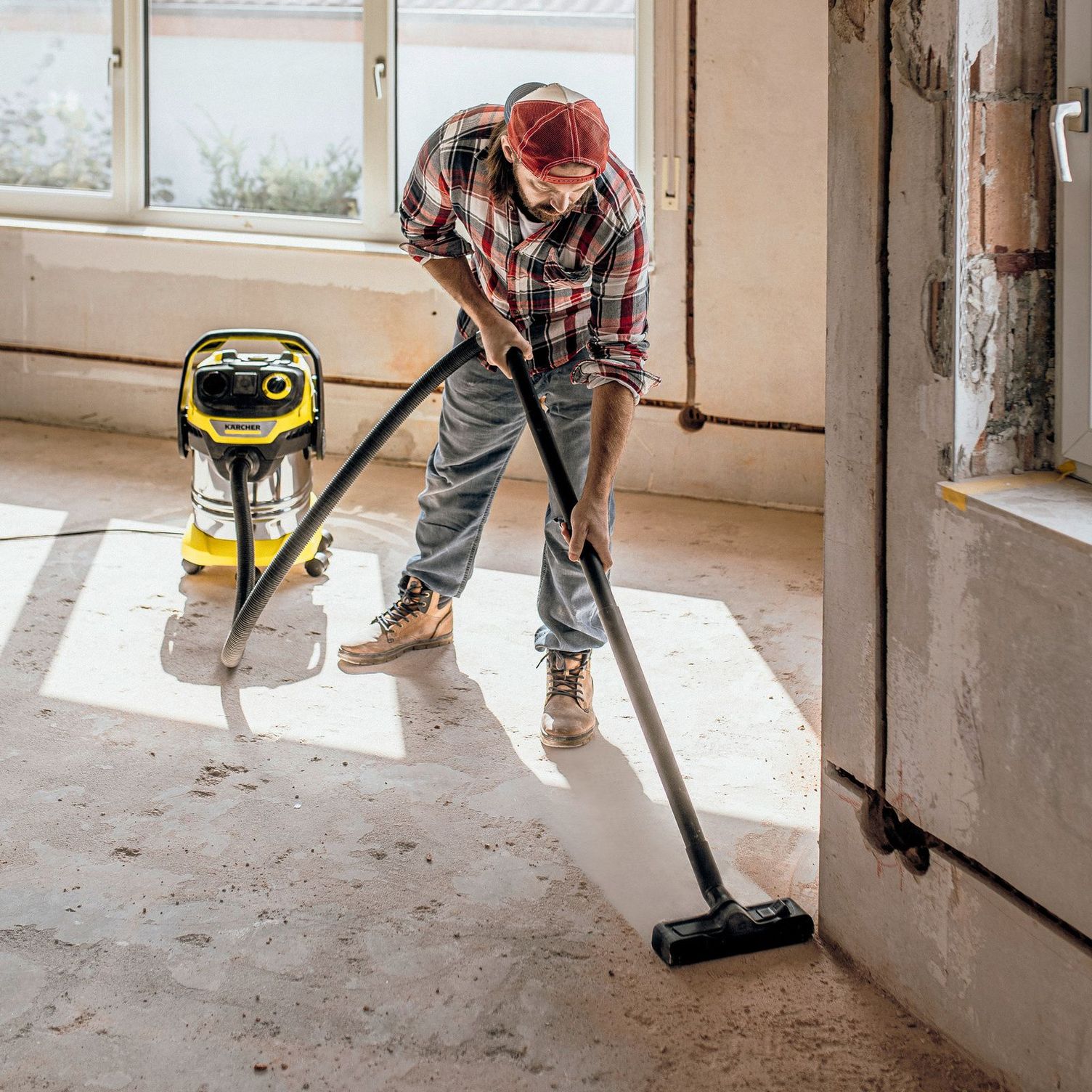 Person cleans construction site with wet and dry vacuum cleaner Kärcher multi-purpose vacuum cleaners