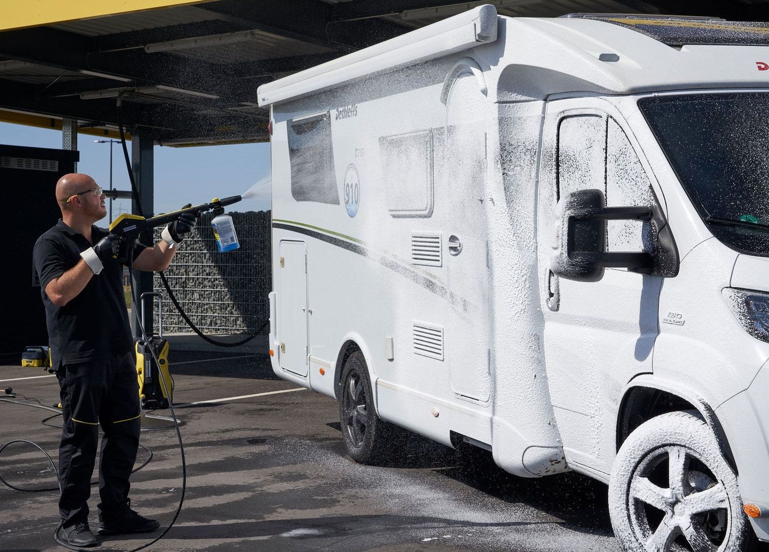 A man cleans his caravan with a Kärcher pressure washer