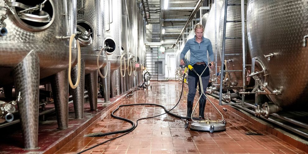 A man cleans the floor in the wine cellar with a Kärcher surface cleaner