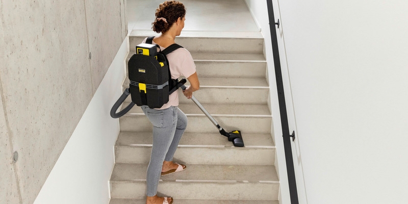 Person vacuuming stairs with the battery powered backpack vacuum cleaner Person vacuuming stairs with the battery powered backpack vacuum cleaner