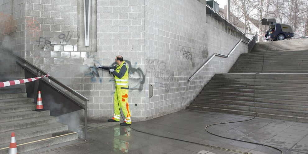 A person removes graffiti from an underpass
