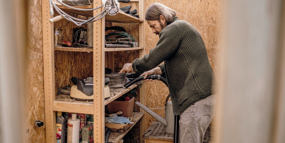 A man vacuums a shelf in his shed