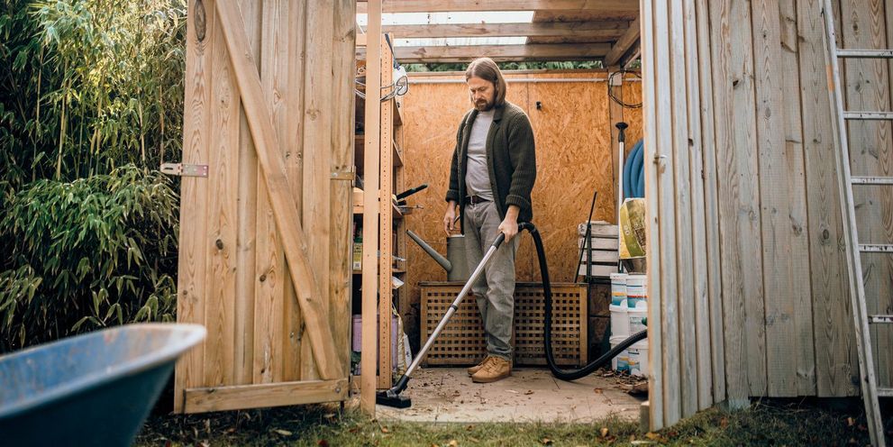 A man vacuums his shed with a Kärcher wet and dry vacuum cleaner
