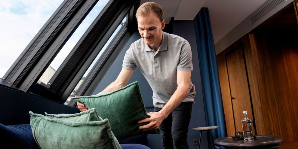 A man puts a pillow on a sofa