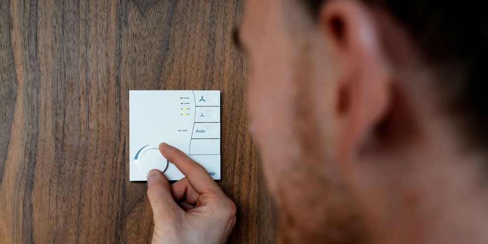 A man adjusts the room temperature on a dial