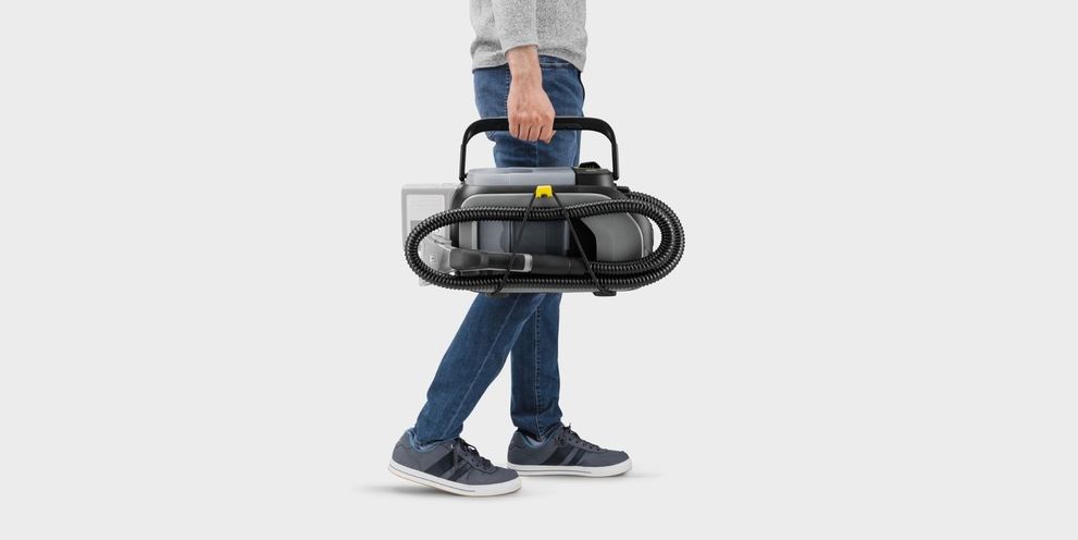 A man carries a Kärcher Puzzi 9/1 Bp A man carries a Kärcher Puzzi 9/1 Bp