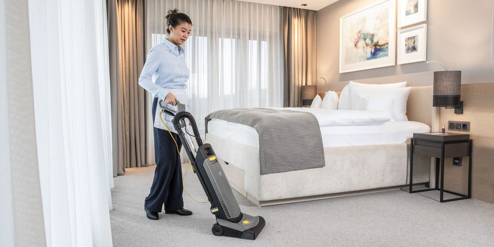 Cleaning in hotel room with carpet vacuum sweeper