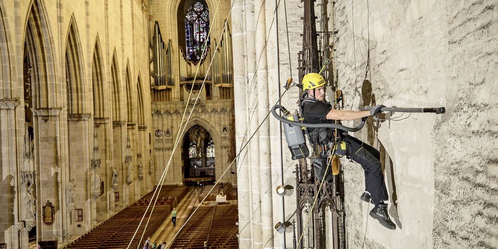 Restorative cleaning of a wall using a rope access technique A person cleans a wall