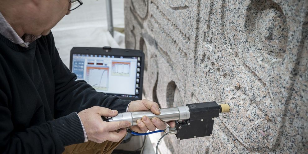 Preliminary assessments of a monument before restoration cleaning A person examines the condition of a monument