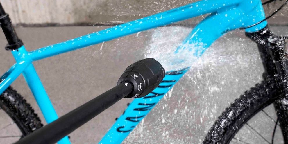 Step 2: Clean bike with water A light blue bike is cleaned with a Kärcher pressure washer